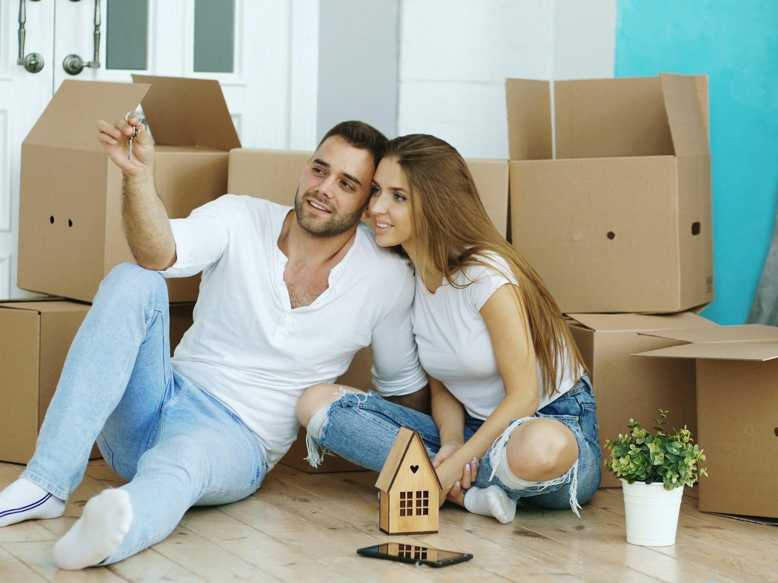 A couple sitting on the floor of a new home among moving boxes