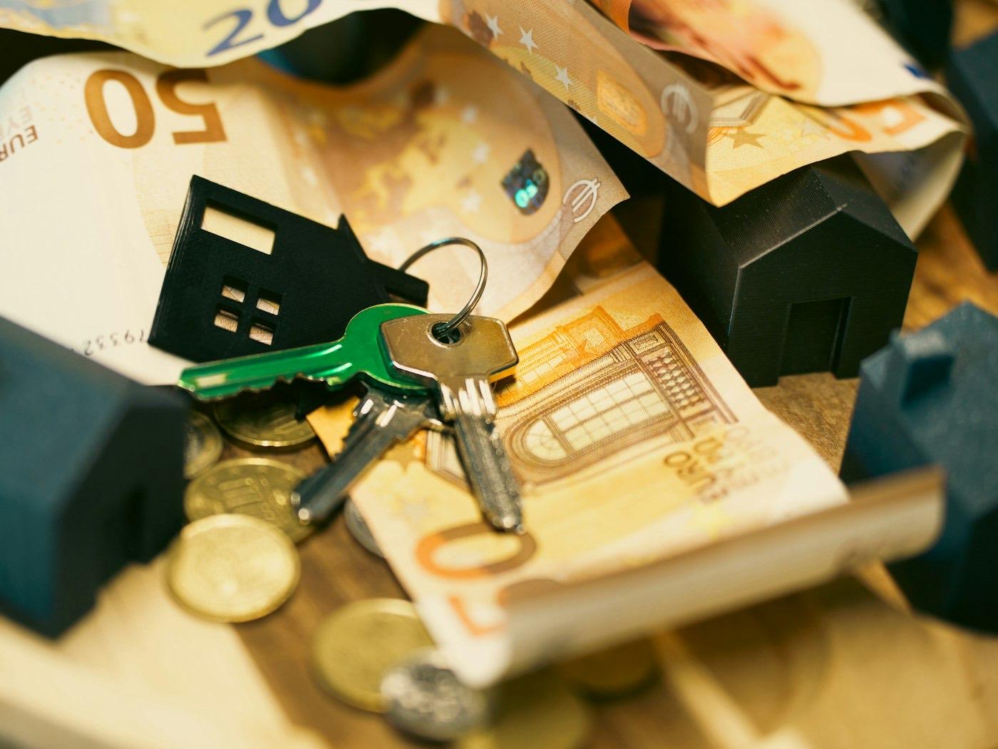 House keys beside savings and a small model house on a table
