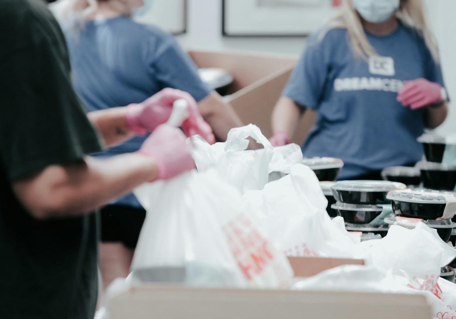 Volunteers in work gloves packing bags of food for neighbors